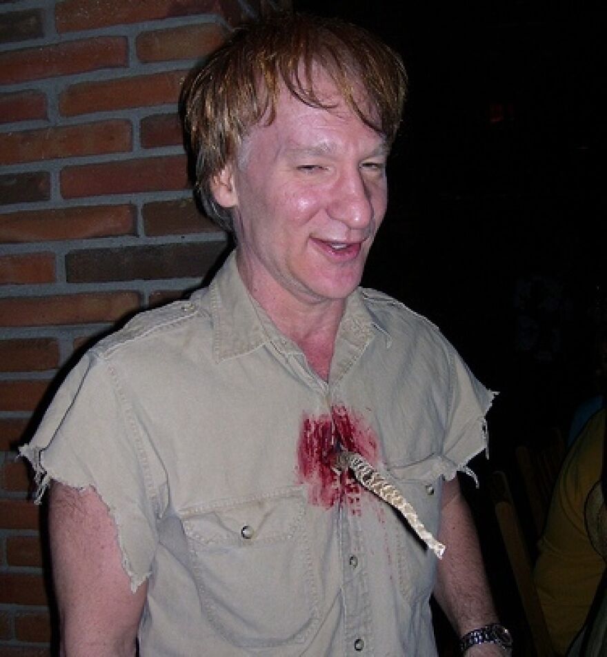 Man wearing a makeshift Halloween costume with a fake knife and blood on shirt, showing unusual common sense choices.