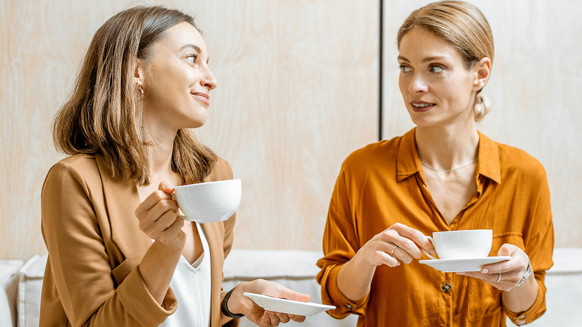 Two women having coffee while one embarrasses new colleague by speaking in a language she claimed to know well