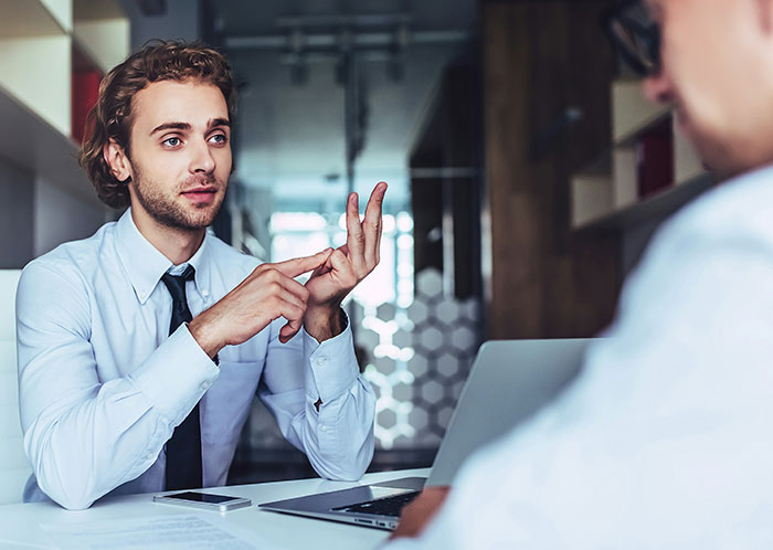 Man in office explaining something with hand gestures to new colleague during a language misunderstanding discussion. Man in office explaining something with hand gestures to new colleague during a language misunderstanding discussion.