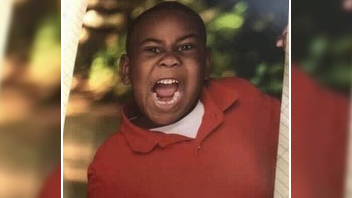 Child in a red shirt laughing loudly, showcasing kids outsmarting grown-ups in an entertaining outdoor setting.