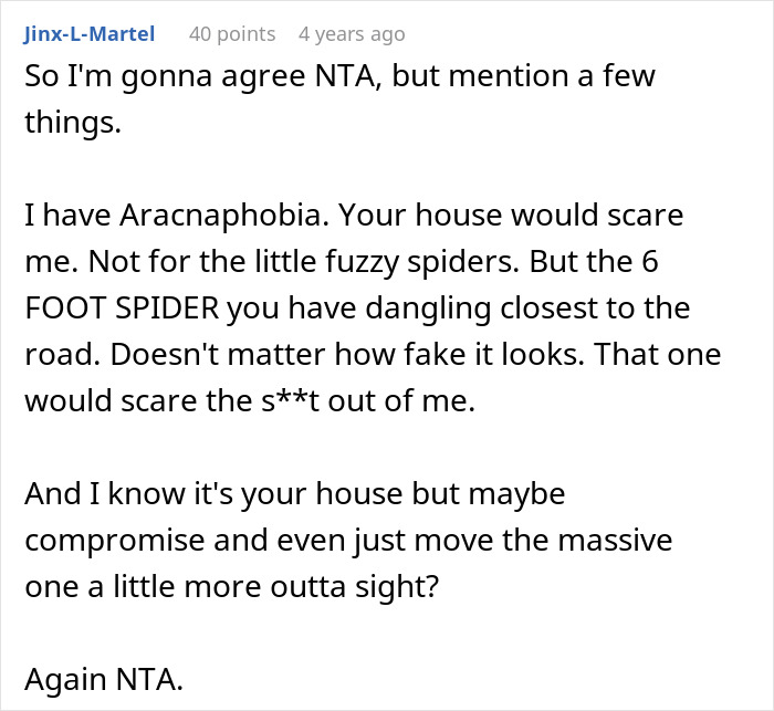 Red and green Halloween spider decoration hanging outside a house, part of elaborate Halloween decor.