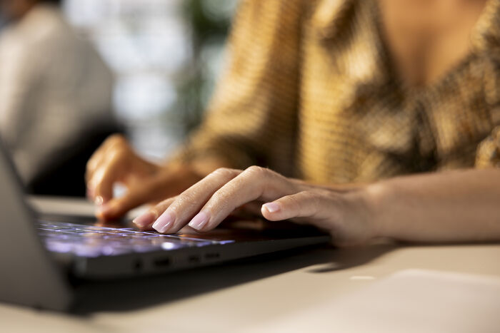 A woman in a patterned blouse typing on a laptop keyboard, related to boss wife claim and innocent worker. A woman in a patterned blouse typing on a laptop keyboard, related to boss wife claim and innocent worker.