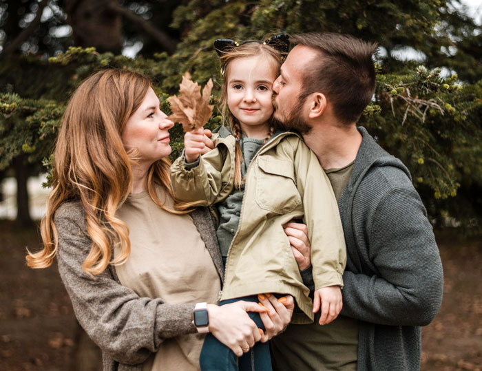 Parents holding and showing affection to their child outdoors, reflecting emotions related to confront parents DNA test. Parents holding and showing affection to their child outdoors, reflecting emotions related to confront parents DNA test.