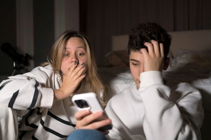 Two teenagers looking shocked and worried while checking phone results, facing confront parents DNA test situation. Two teenagers looking shocked and worried while checking phone results, facing confront parents DNA test situation.
