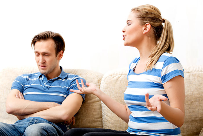 Wife expressing frustration to husband on couch, highlighting challenges of cleaning bed repeatedly without his cooperation. Wife expressing frustration to husband on couch, highlighting challenges of cleaning bed repeatedly without his cooperation.