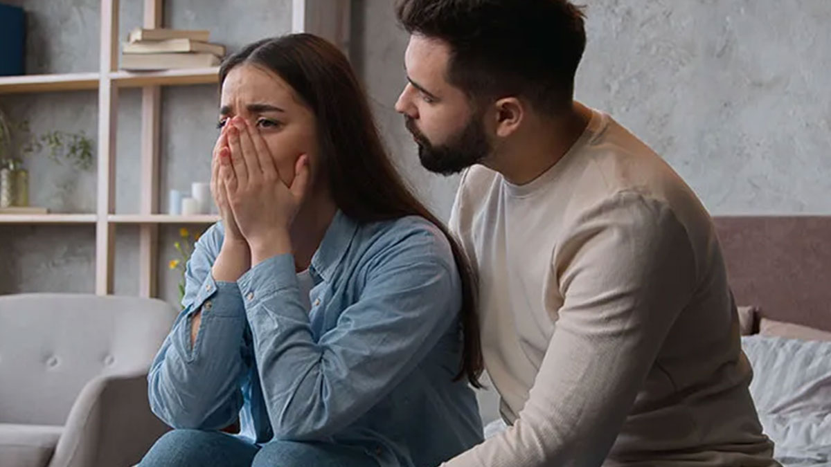 Woman upset covering her face while husband comforts her, depicting tension leading to marriage falling apart.