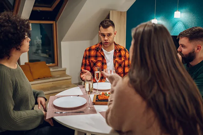 Couple having tense dinner conversation, husband threatening divorce while wife’s parents look concerned at table.