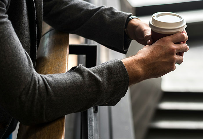 Man in a gray jacket holding a coffee cup, symbolizing tension related to husband threatens with divorce and marriage issues.