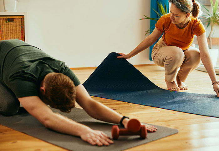 Couple practicing yoga on mats at home, highlighting tension and challenges in their marriage during shared activities.