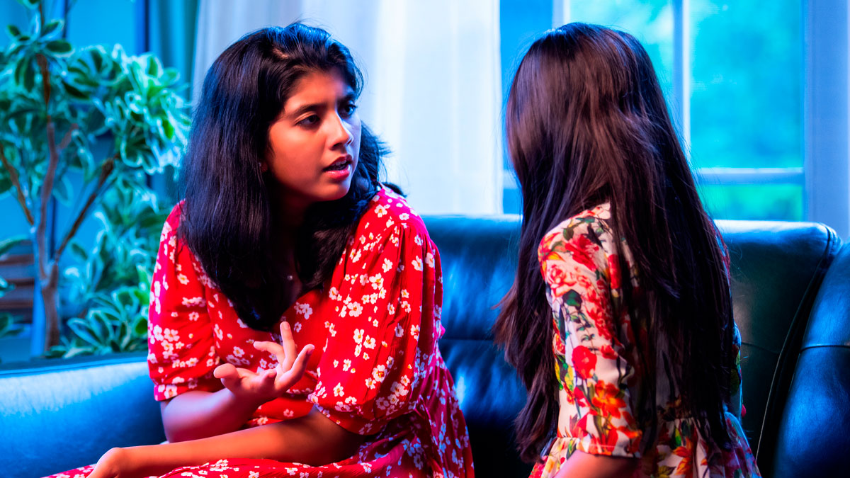 Two women having a serious conversation on a couch, illustrating woman gleams watching cousinu2019s wife struggle.