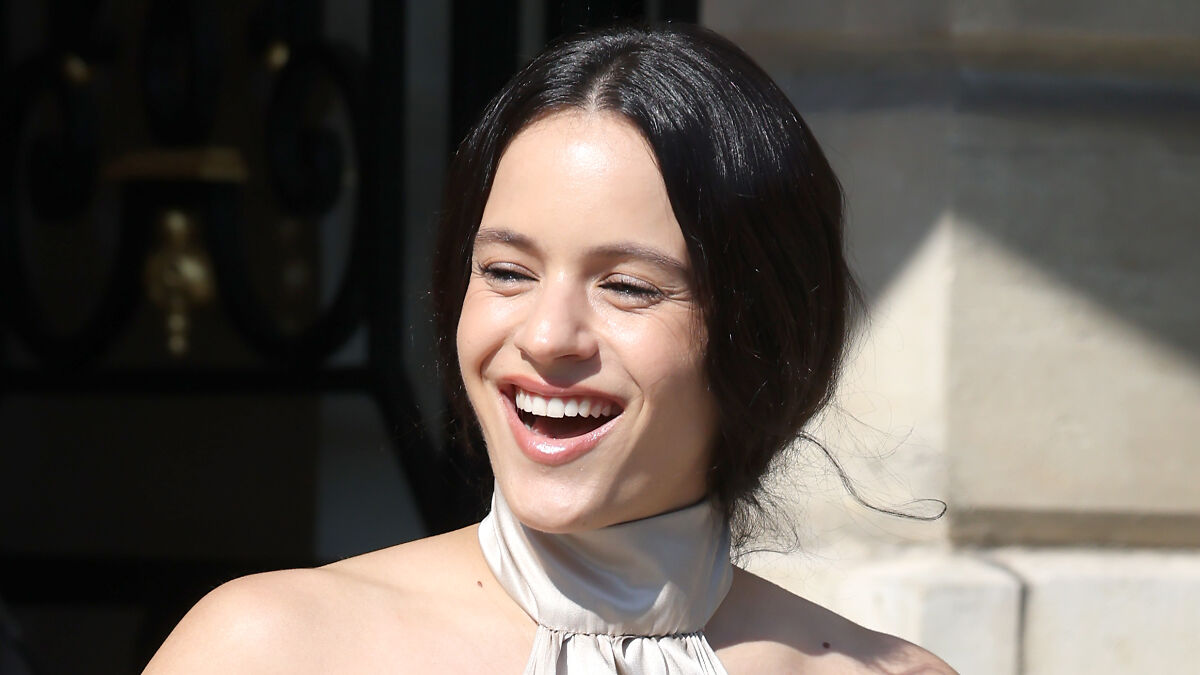 Pop star smiling at Paris Fashion Week event, known for dyeing her armpit hair, sparking mixed reactions from fans.