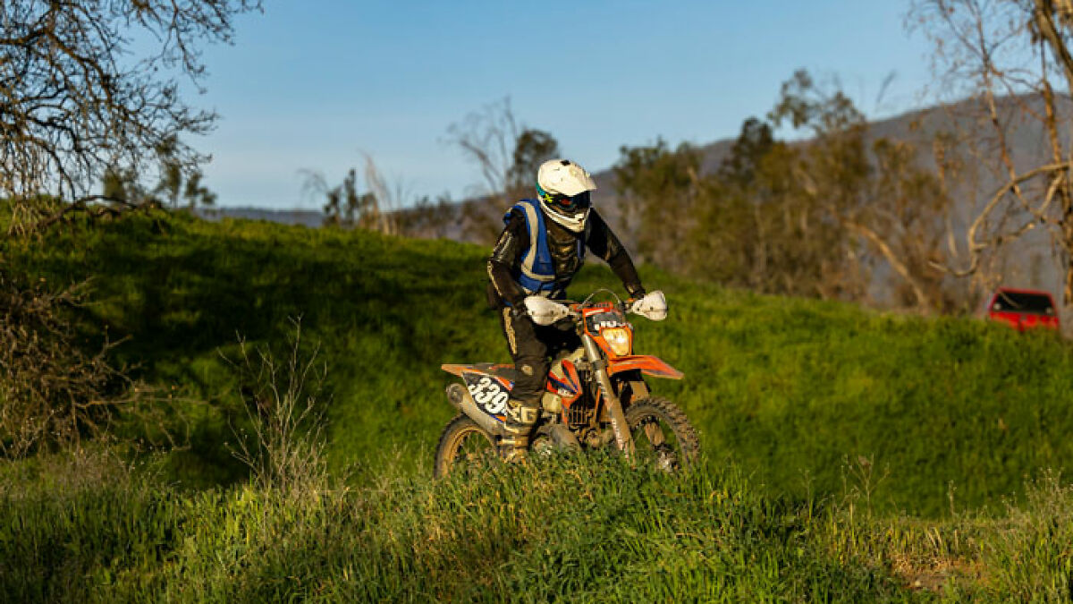 Person on dirt bike riding through wilderness area, highlighting people suspicious after missing hiker found roaming in underwear.