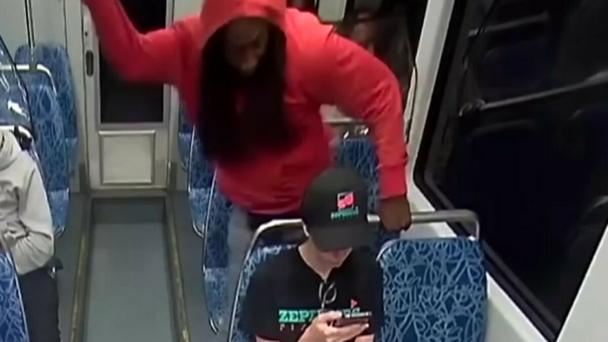 Person in red hoodie raising arm aggressively on bus, capturing chilling attack moment linked to Iryna Zarutska horror panic.