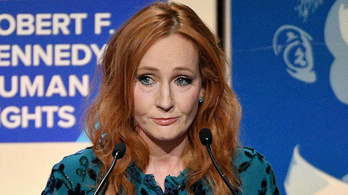 J.K. Rowling speaking at a podium during a human rights event, with red hair and a serious expression.