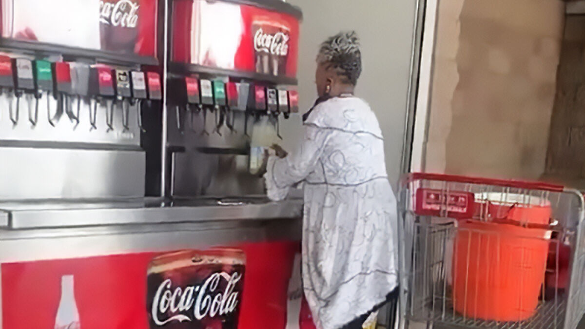 Woman filling huge container with Costco soda refills at soda fountain, sparking debate over store policy and usage.
