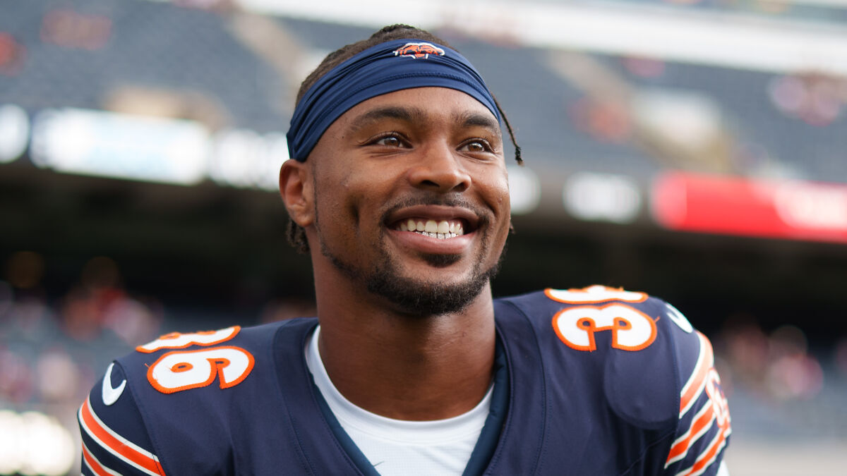 Jonathan Owens smiling in Chicago Bears uniform on the field, showcasing power couple net worth growth.