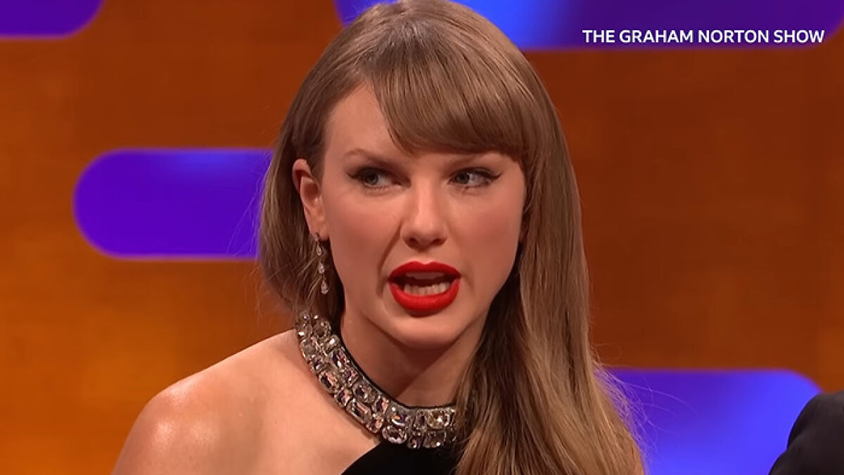 Taylor Swift speaking on the Graham Norton show, wearing a jeweled dress and bold red lipstick.