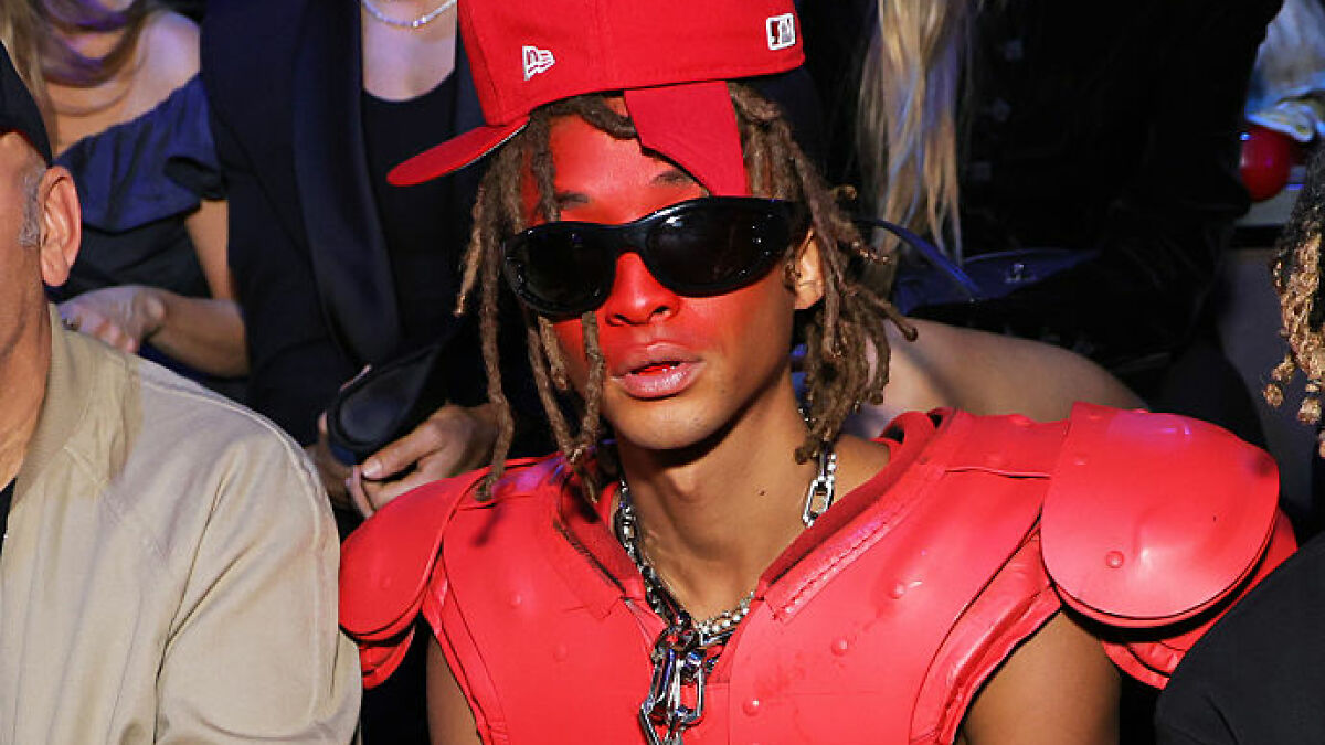 Jaden Smith wearing red face paint and a red outfit with oversized sunglasses at a crowded event in Paris.