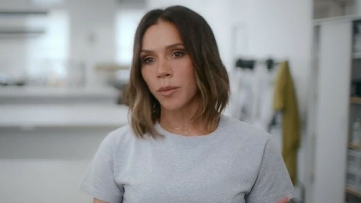 Victoria Beckham in a casual gray shirt, explaining why she never smiled after being labeled a miserable cow in a bright room.