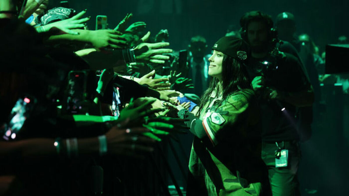 Billie Eilish interacting with fans on stage at a Miami concert amid outrage over snatching incident.