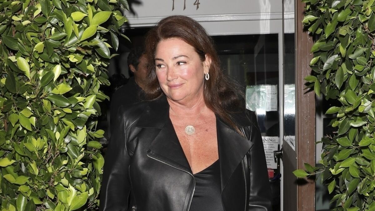 Pierce Brosnan's wife showing off her slimmer-than-ever frame at 62 wearing a black leather jacket outdoors at night.
