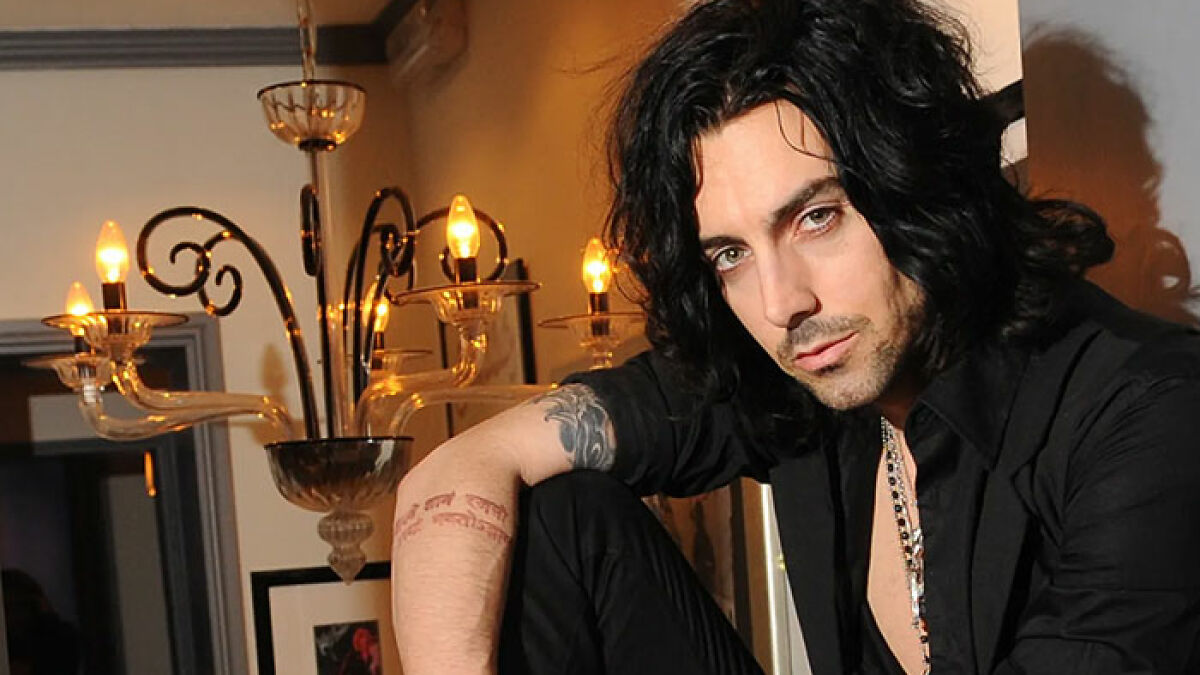 Rock star with dark hair posing indoors near a chandelier, related to prison and crimes against children keywords.