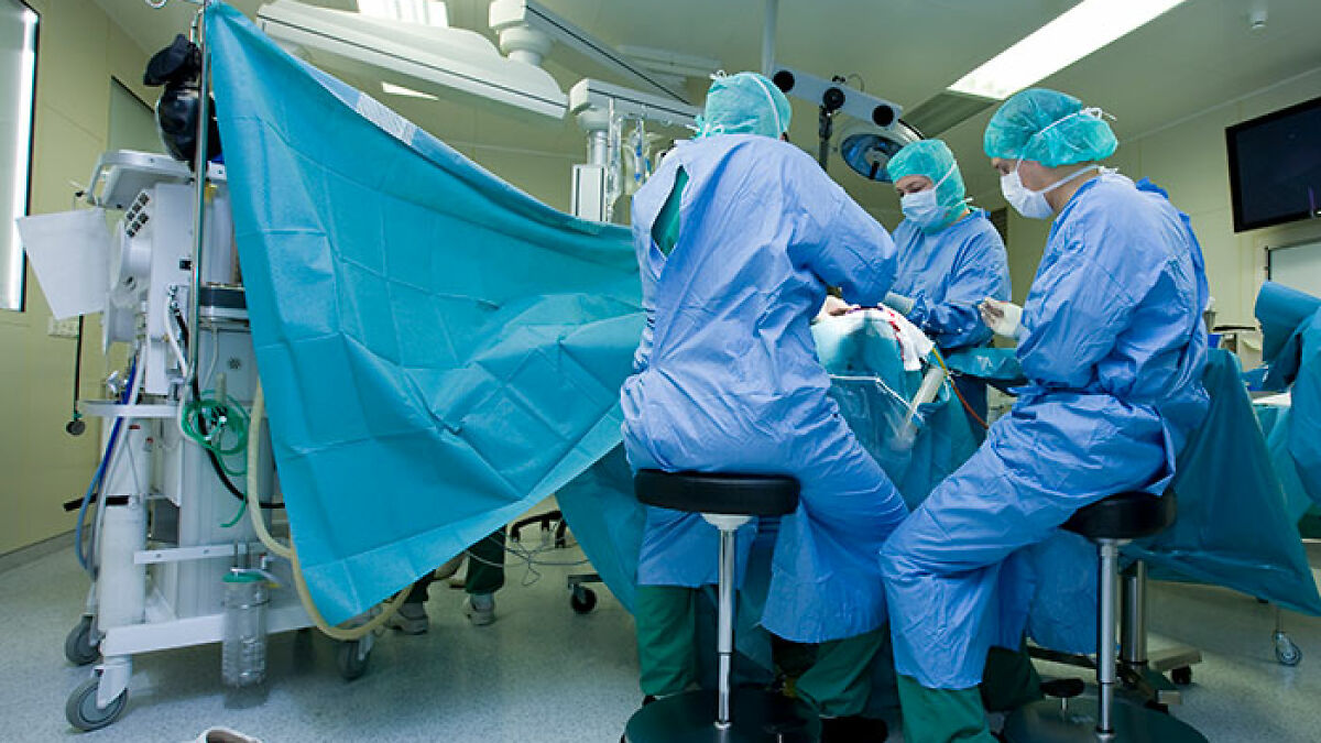 Brain surgeons and medical team perform a complex surgery in an operating room with sterile blue surgical gowns and equipment.