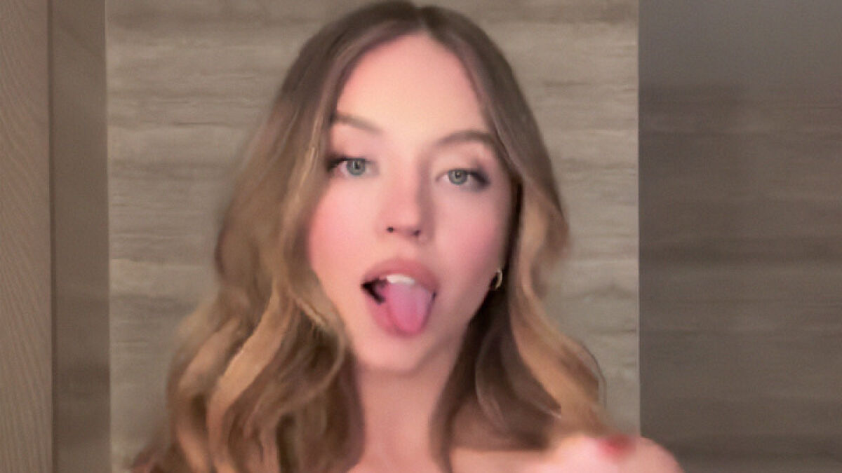 Sydney Sweeney showing her cleavage makeup trick in a viral beauty tutorial video with styled hair and natural lighting.