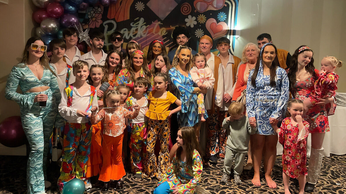 Large family dressed in colorful retro outfits posing indoors, highlighting parents of 22 after $70,000 Disney vacation court dispute