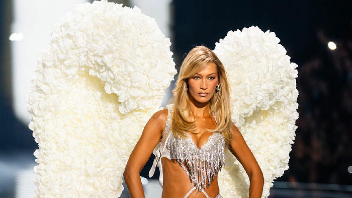 Model wearing large white Victoriau2019s Secret angel wings made of flowers on runway during fashion show.