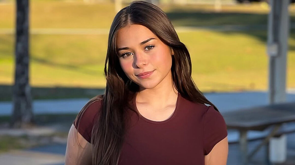 Young adult star Sophie Rain outdoors in natural light, wearing a maroon top, highlighting her success without unclothed content.