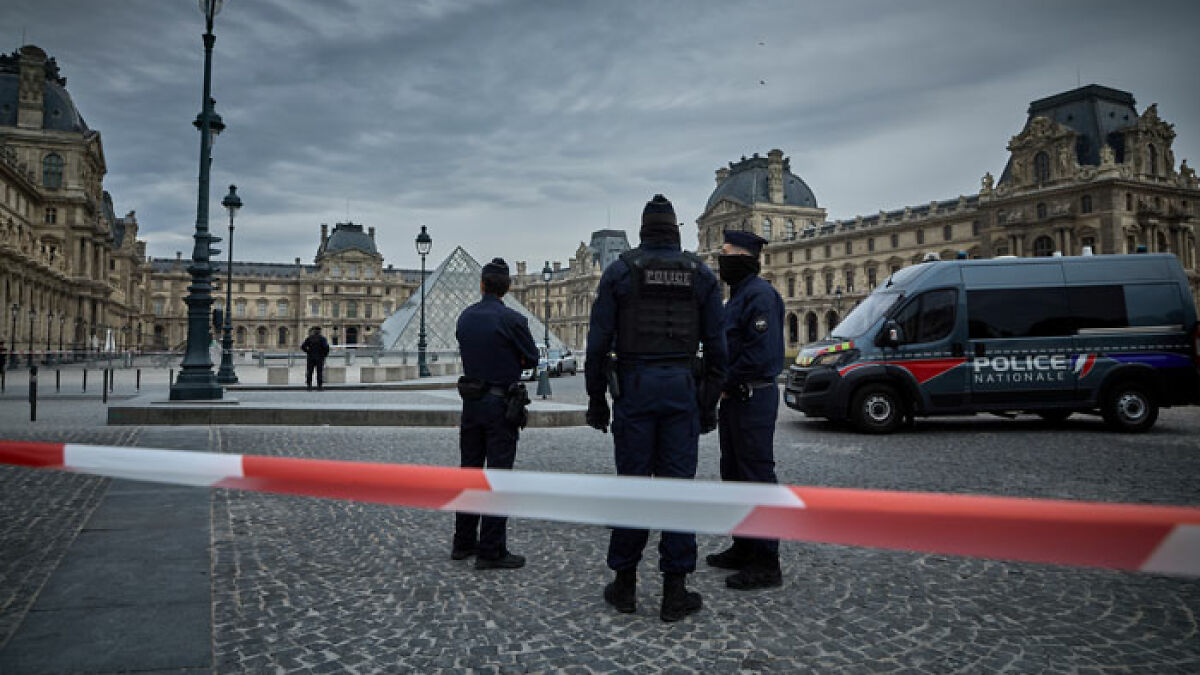 Police officers stand outside the Louvre Museum near the glass pyramid after a daylight heist involving priceless jewels.