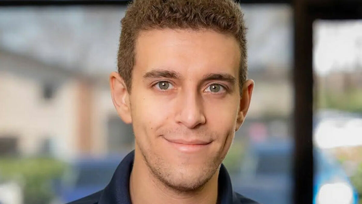 Daniel Naroditsky American chess grandmaster smiling with a blurred indoor background in soft natural light