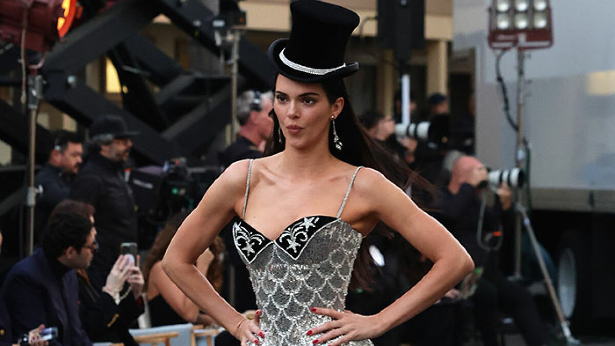 Model wearing a silver patterned dress and black top hat, showcasing one of the worst and weirdest celebrity looks at Vogue World.