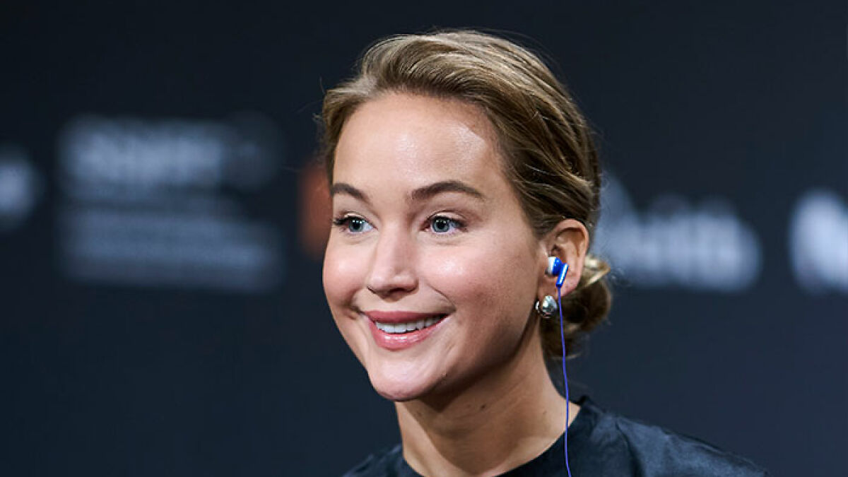 Jennifer Lawrence smiling with earbuds, speaking publicly about plastic surgery plans after viral video surprised fans.