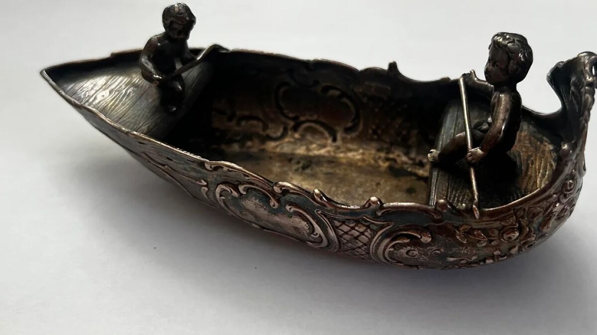 Antique decorative metal boat with two small figures rowing, an unexpected find while cleaning a vintage collection.