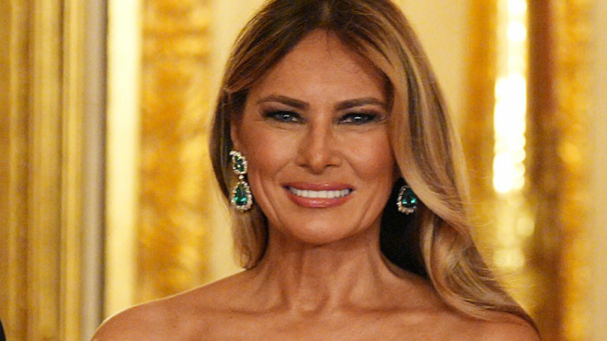 Melania Trump smiling at a formal event with gold decor, related to White House Halloween display reactions.