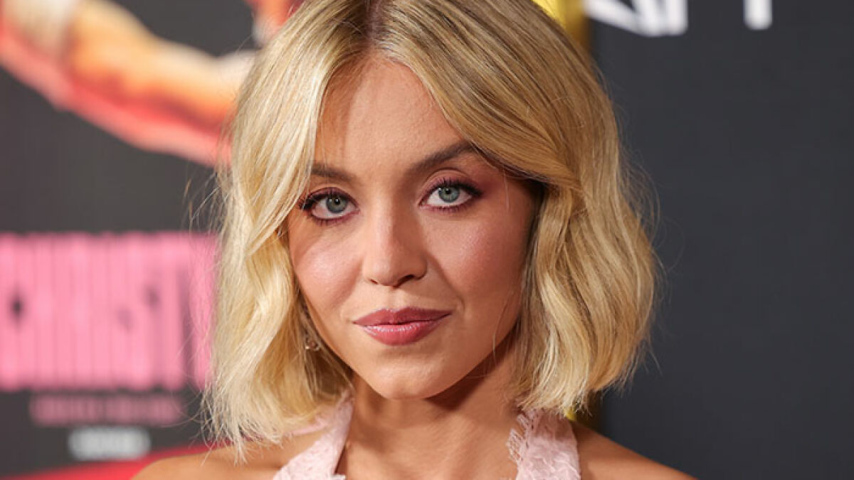 Sydney Sweeney at an event with blonde hair, wearing makeup and a pink top, related to pro-modesty controversy.