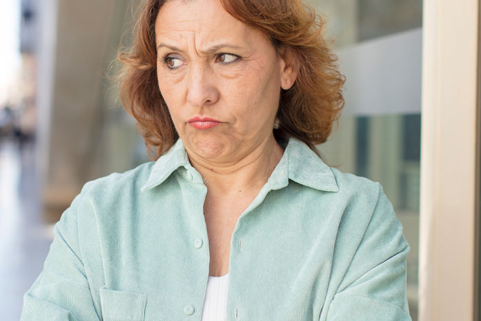 Middle-aged woman with a skeptical expression standing outside, reflecting feelings of being scammed at a show event. Middle-aged woman with a skeptical expression standing outside, reflecting feelings of being scammed at a show event.
