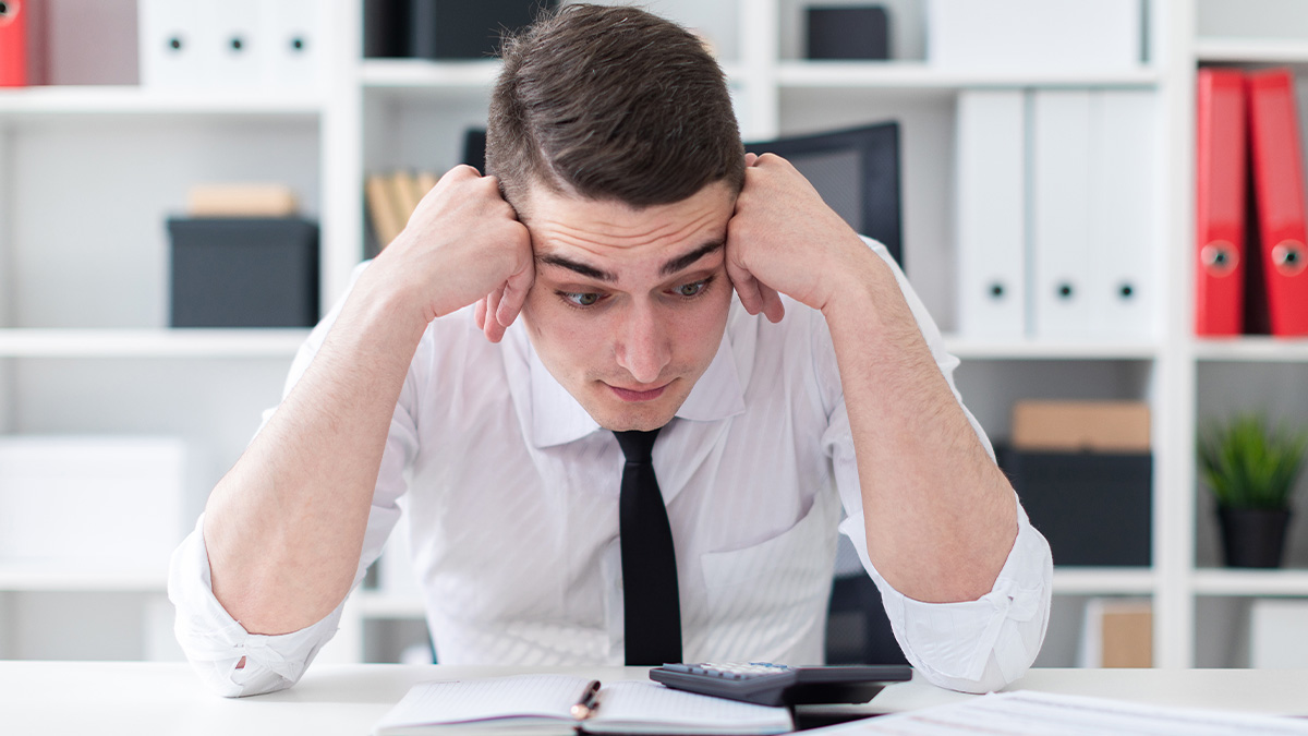 Accountant looking stressed at desk with calculator and documents, challenging notions of boring accounting jobs.
