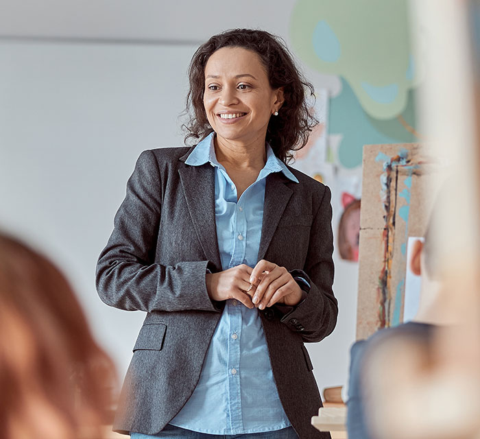 Smiling businesswoman in a gray blazer speaking to colleagues in an office, illustrating work nepotism cases witnessed.
