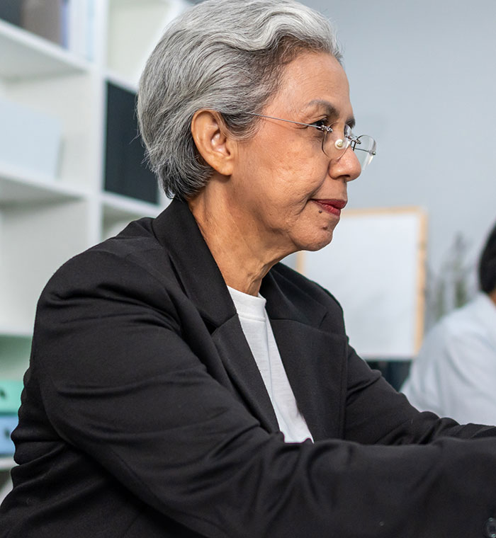 Older woman in glasses working in an office environment, representing work nepotism in professional settings.