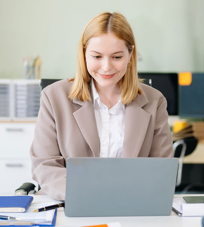 Young professional woman working on a laptop at office desk, illustrating common scenarios of work nepotism in the workplace.