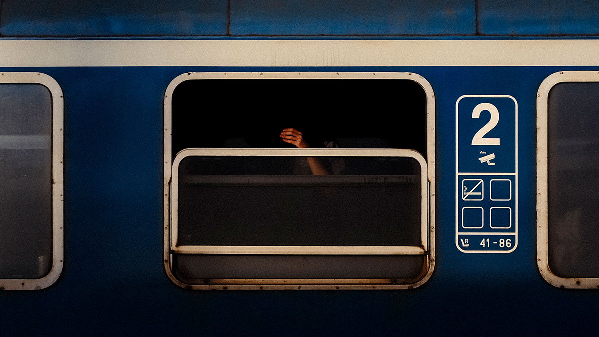 Hand reaching out of a dark train window in a street photo capturing the magic of everyday life by Gianluca Mortarotti.