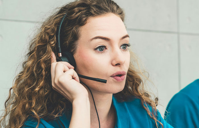 Woman with curly hair wearing a headset, focused on creepy found footage and videos, possibly during a call or review session.