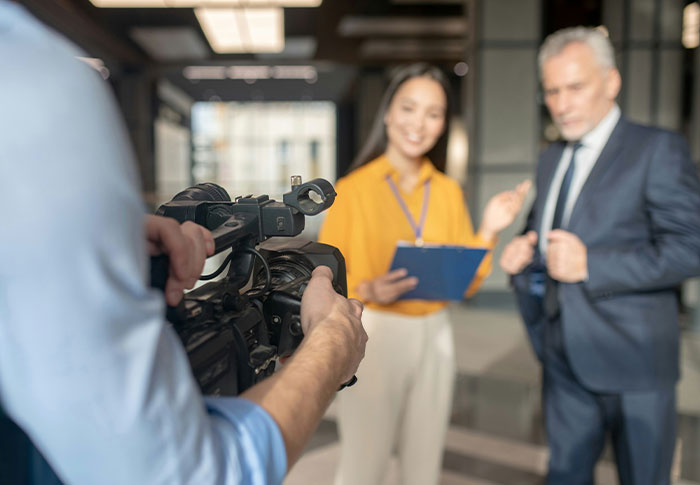 Camera operator filming an interview with two professionals, focusing on found footage and creepy video storytelling.