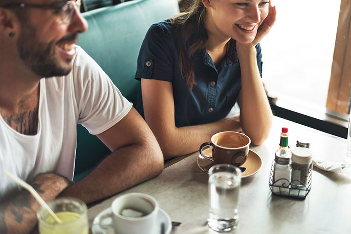 Two people smiling at a cafe table with drinks, illustrating a man drawing a line over family conflict.