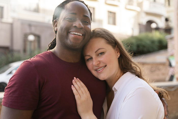Biracial couple smiling outdoors, highlighting themes of biracial identity and parenting challenges with hair care. Biracial couple smiling outdoors, highlighting themes of biracial identity and parenting challenges with hair care.