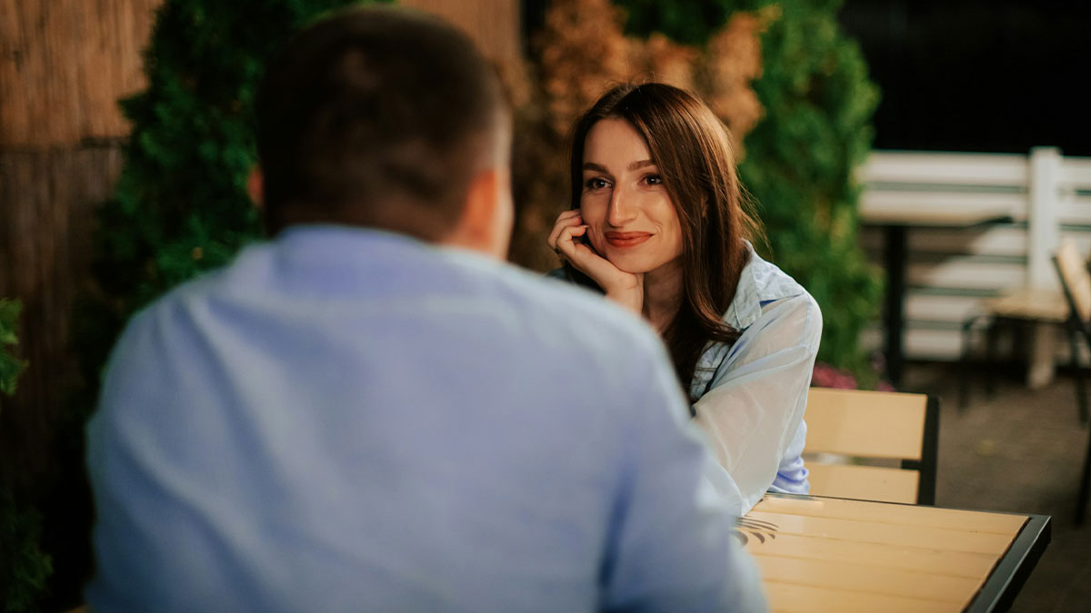 A couple on a date at an outdoor restaurant, engaged in a lighthearted and charming conversation about dating.
