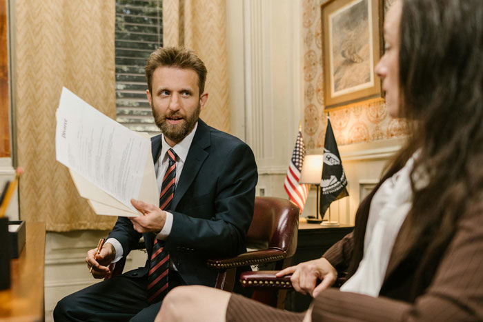 Man in suit holding papers, talking to woman during a serious discussion about dating men with kids and priorities. Man in suit holding papers, talking to woman during a serious discussion about dating men with kids and priorities.
